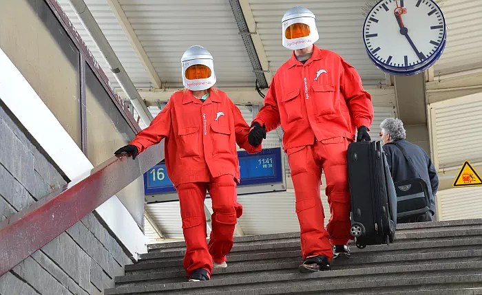 Zwei Personen im Alterssimulationsanzug Age Explorer auf einer Treppe.
